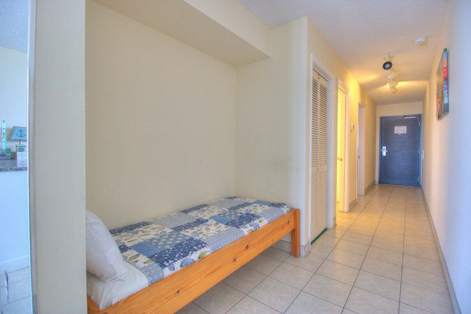 A narrow hallway with a single bed in a room.