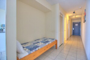 Ein schmaler Gang mit einem Einzelbett in einem Zimmer.