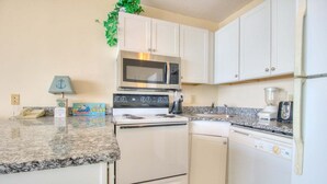Cocina compacta con estufa, microondas, lavavajillas y una pequeña zona de encimera.