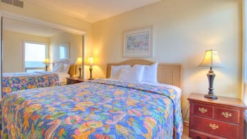 A hotel room with two beds, a dresser, a mirror, and a painting on the wall.