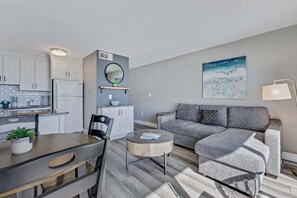 A modern apartment with a kitchen, dining area, and a living room with a sofa and a coffee table. - Oceanfront 1 Bedroom Retreat in Carolina Beach - Perfect for a cozy getaway! (Carolina Beach)