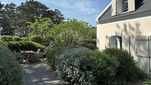 Una casa amb jardí, taula de fusta i una porta.