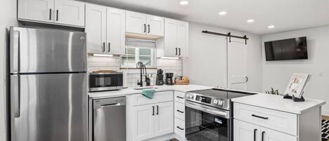 Una cocina moderna con armarios blancos, electrodomésticos de acero inoxidable y horno empotrado.