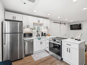 Una cocina moderna con armarios blancos, electrodomésticos de acero inoxidable y horno empotrado.