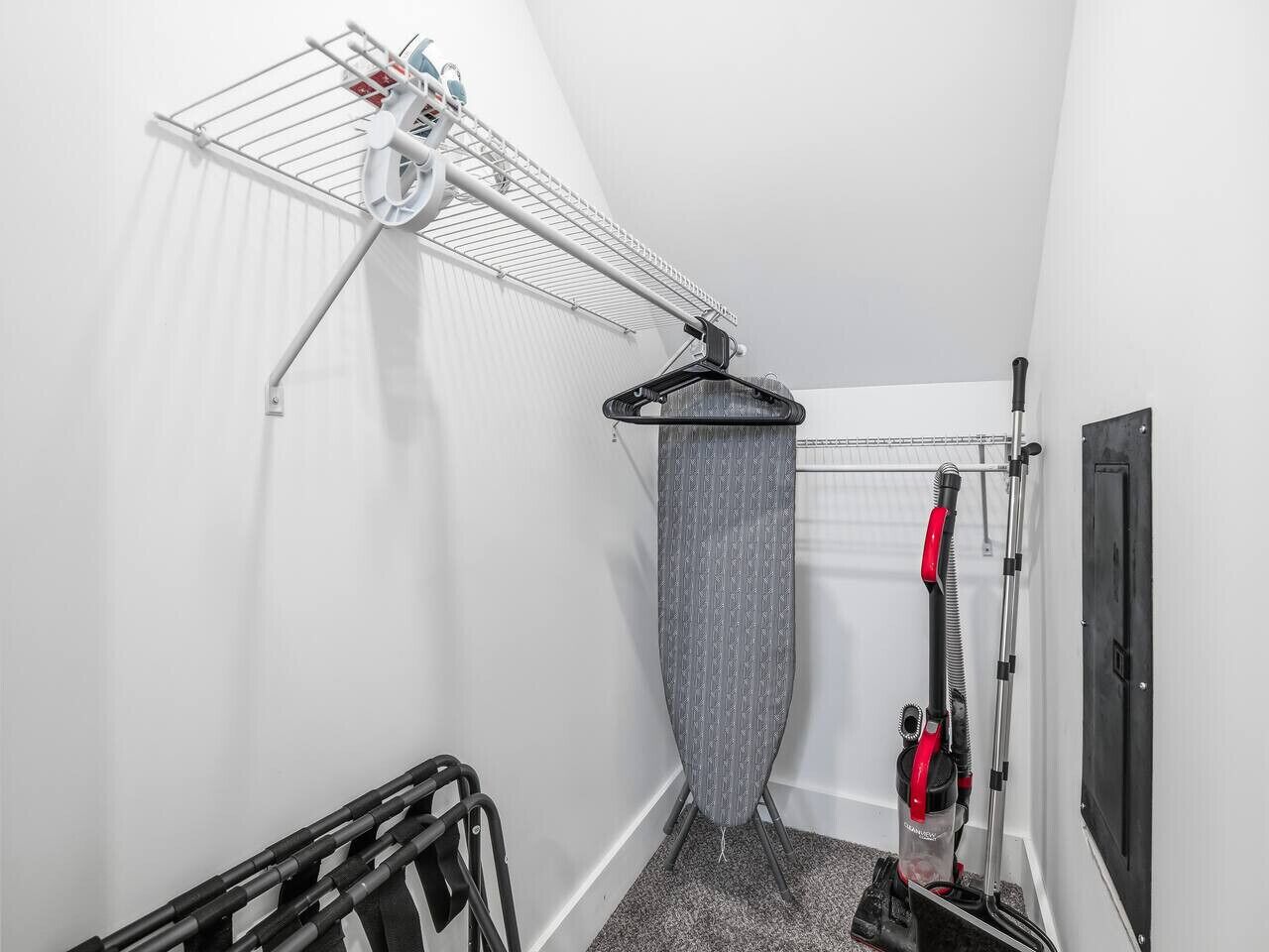 A narrow hallway with a ceiling-mounted drying rack, a hanging shower curtain, and a vacuum cleaner.