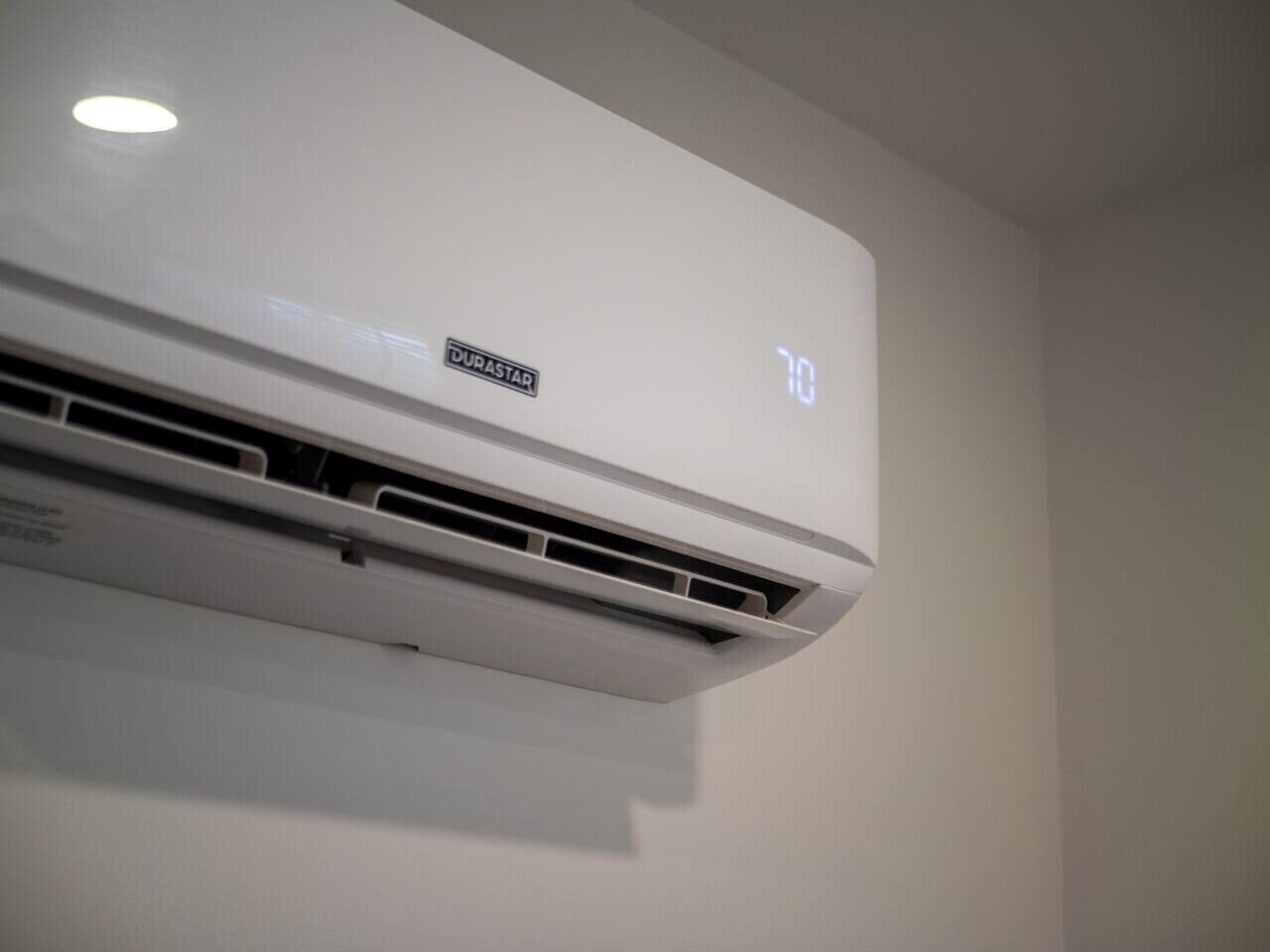 Un appareil de climatisation blanc, fixé au mur, avec un panneau de commande indiquant le réglage de la température.