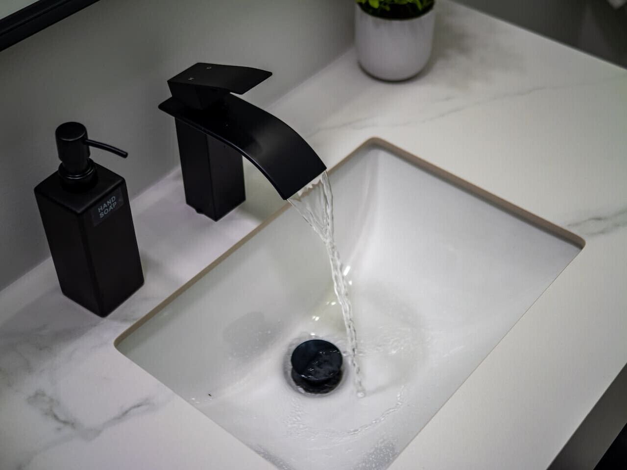 Et moderne badeværelsesarrangement med en sort hane og sæbedispenser.
