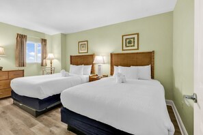 A hotel room with two beds, a dresser, a window with curtains, and wall-mounted lamps. - The Caribbean Resort and Villa 1408 (Myrtle Beach)