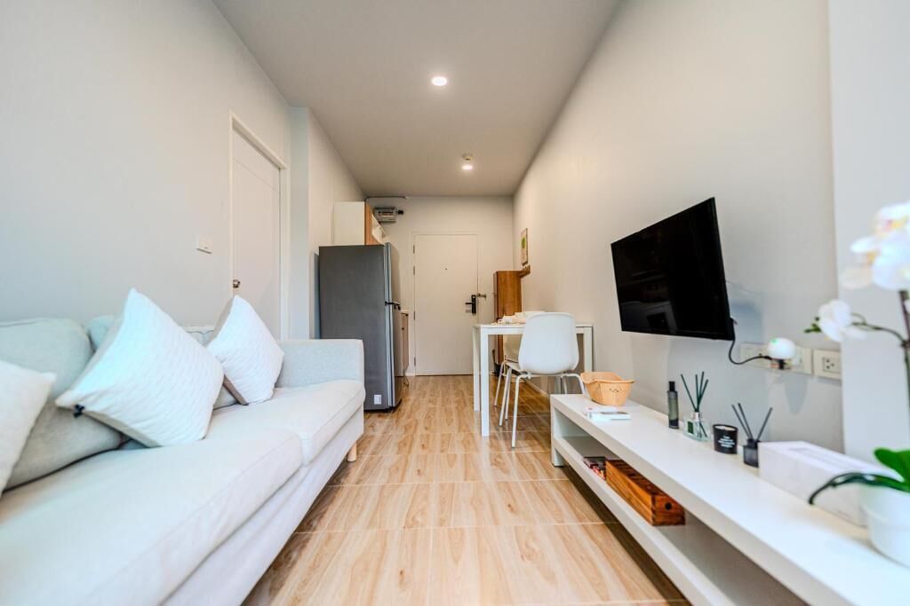 Un espace de vie moderne et compact, comprenant un canapé, un téléviseur et un petit coin repas.