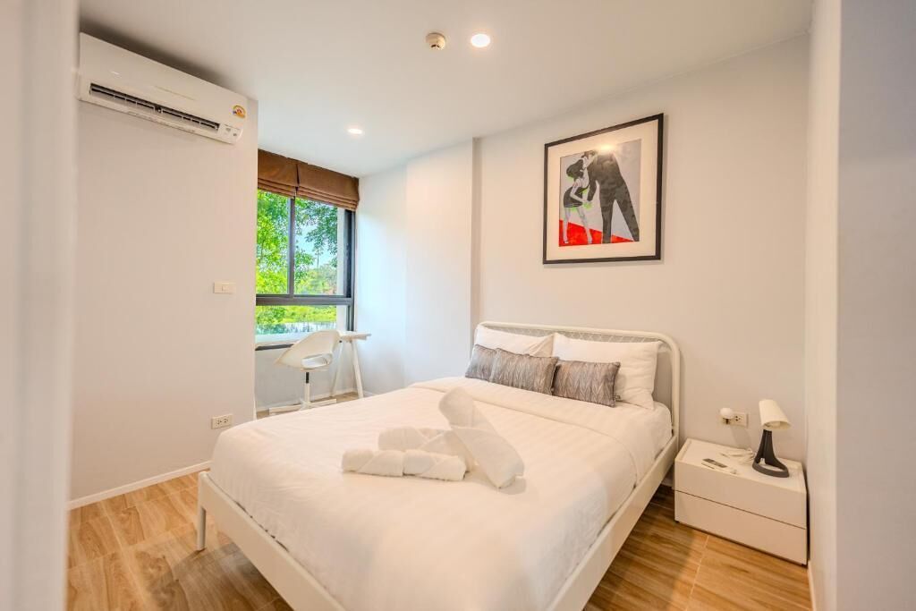 Un dormitorio moderno con una cama, mesitas de noche, una silla y un ventanal.