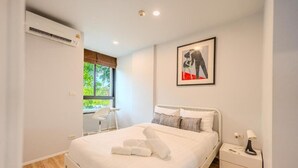A modern bedroom with a bed, bedside tables, a chair, and a window. - ZcapeX2 (Choeng Thale)