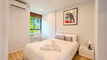 Un dormitorio moderno con una cama, mesitas de noche, una silla y un ventanal.