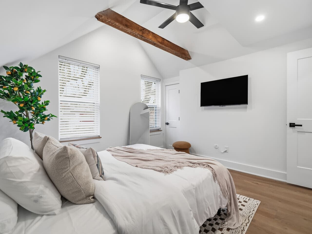 Un dormitorio con cama, televisión, ventilador de techo y ventana con persianas.