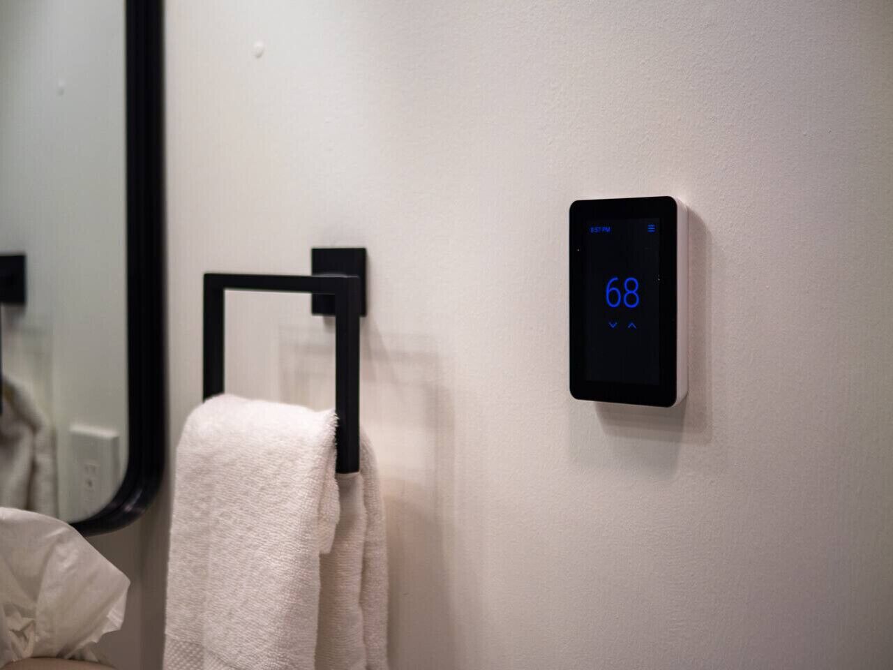 Un baño con toallero y termostato digital que muestra la temperatura.