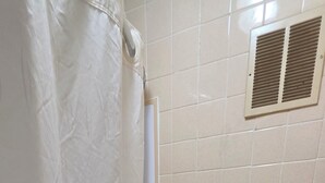 Une salle de bain équipée de toilettes, d’un rideau de douche, d’une baignoire et d’un porte-serviettes.