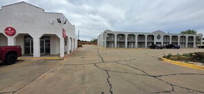A hotel with a sign for 'Deluxe Inn,' a parking lot with several cars, and a building with multiple balconies. - DELUXE INN SHAMROCK (Shamrock)