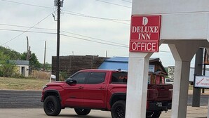 Un VUS rouge était garé près d’un bâtiment sur lequel on pouvait lire l’inscription « Bureau du Deluxe Inn ».