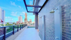 A modern building with a balcony, a brick wall, and a cityscape view. - Vol 29 - Miramar Hospedagens (João Pessoa)