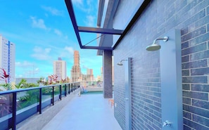 A modern building with a balcony, a brick wall, and a cityscape view. - Vol 29 - Miramar Hospedagens (João Pessoa)