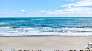 Ein Strand mit einem Rettungsturm, blauem Himmel und ruhiger See.