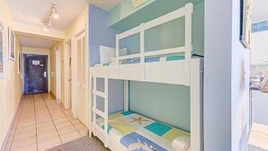 A bunk bed room with a ladder, a door, and a wall with a sign. - Oceanfront 1-bedroom condo in Carolina Beach 0806 (Carolina Beach)