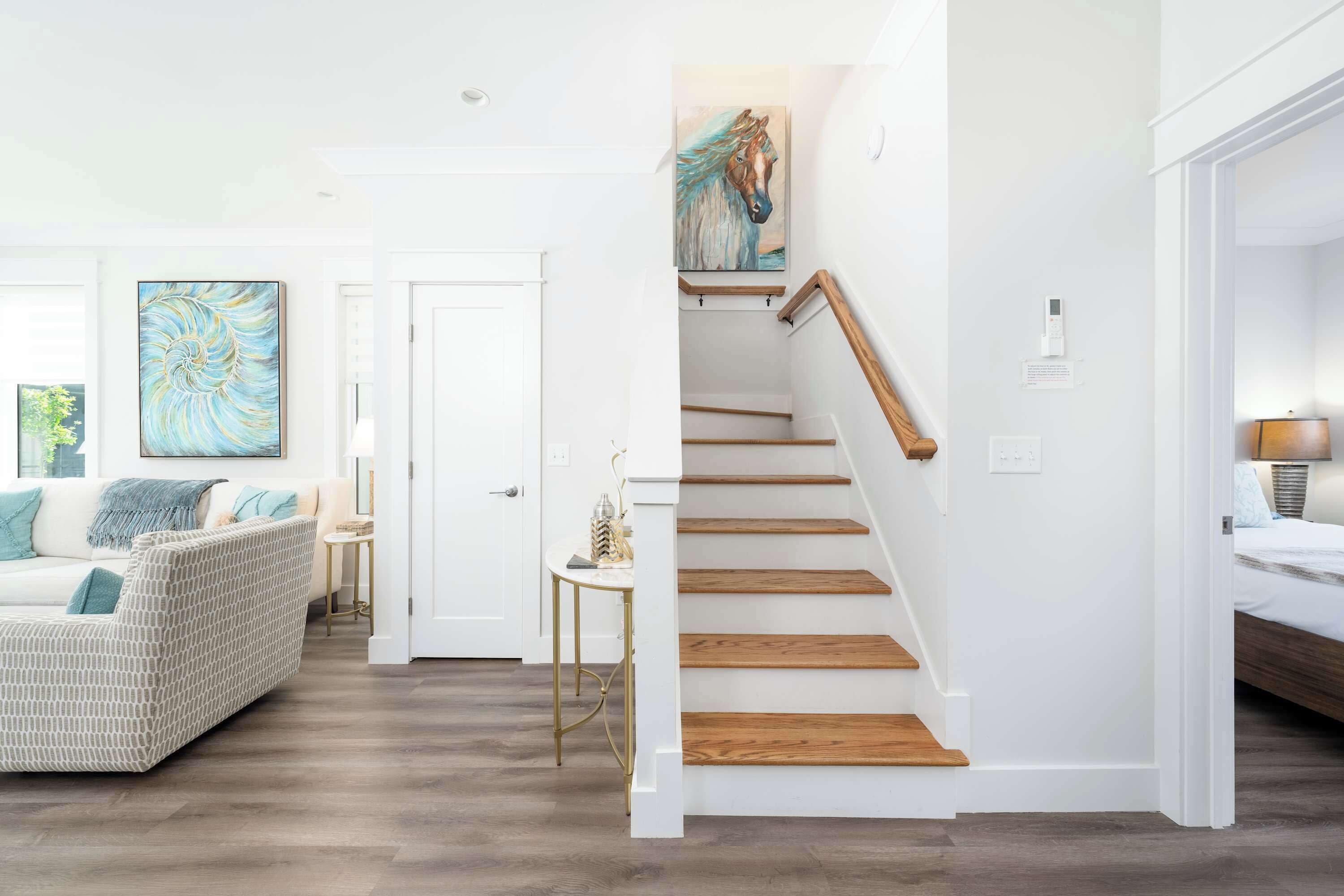 A modern interior with a staircase, a sofa, and artwork.