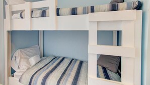 A bunk bed with a striped bedspread and pillows. - Cozy 1 Bedroom Oceanfront Condo at Carolina Beach 0809 (Carolina Beach)