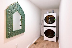 A laundry room with a large mirror and two stacked washing machines. - Spacious 4BR Family Home with Game Room (Raleigh)