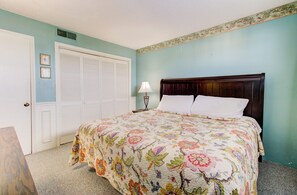 Ein Schlafzimmer mit Bett, Nachttisch, Lampe, Schrank und einer Tür.