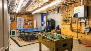 Ein Zimmer mit Tischtennisplatte, Kicker und einem kleinen Hausmodell.