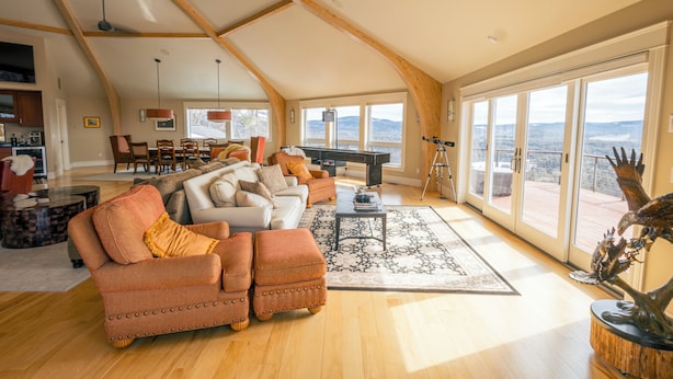 Ein großzügiges Wohnzimmer mit hoher Decke, einem Klavier und großen Fenstern mit Blick ins Freie.
