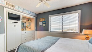 Un dormitorio con cama, armario, ventana con persianas y ventilador de techo.