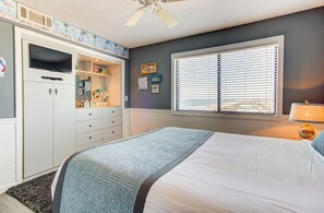 Ein Schlafzimmer mit Bett, Kleiderschrank, einem Fenster mit Jalousien und einem Deckenventilator.
