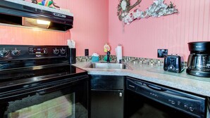 Una cocina con estufa negra, lavavajillas, fregadero y cafetera.