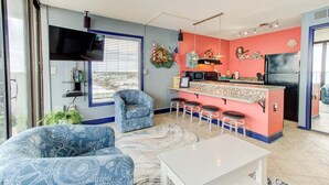 Un espacio habitable compacto con cocina, una zona de estar con un sofá estampado y un televisor montado en la pared.