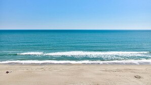 Una playa con cielo despejado, mar tranquilo y orilla arenosa.