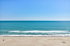 Een strand met heldere lucht, een rustige zee en een zandstrand.