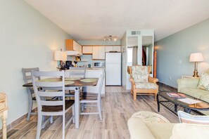 A compact living space with a dining area, kitchenette, and a seating area with a sofa and armchair. - Experience oceanfront bliss at 1002 in Carolina Beach, perfect for 4 guests. (Carolina Beach)