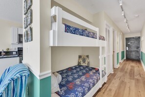 Habitación con literas, una zona de cocina, un pasillo y una puerta que da a otra habitación.