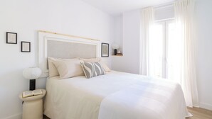 Une chambre à coucher avec un lit, une table de chevet, une lampe et une fenêtre avec des rideaux.