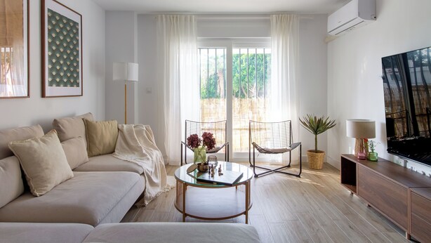 Un salon avec un canapé, une table basse, un téléviseur et une fenêtre avec des rideaux.