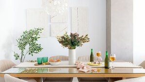 Une table à manger ornée d’un vase de fleurs, de deux bouteilles vertes et de deux verres de bière.