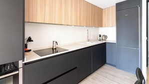 Une cuisine moderne avec un plan de travail noir, des appareils en acier inoxydable et des meubles en bois.