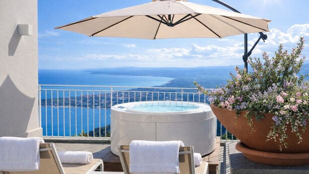 Ein Balkon mit Whirlpool, Liegestühlen, Sonnenschirm und Blumentopf.