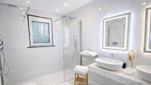 Ein modernes Badezimmer mit einer gläsernen Duschkabine, einem großen Spiegel und einem weißen Waschbecken.