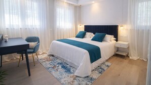 Ein Hotelzimmer mit Bett, Nachttischen, Schreibtisch und Stuhl.