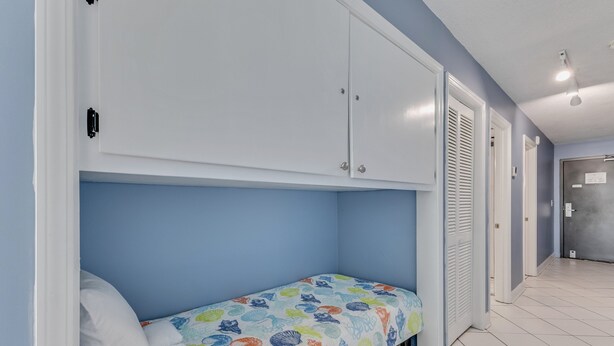 Ein Schlafzimmer mit einem Einzelbett, einem Kleiderschrank und einer Tür zu einem anderen Raum.