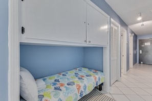 Ein Schlafzimmer mit einem Einzelbett, einem Kleiderschrank und einer Tür zu einem anderen Raum.