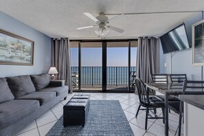 Ein modernes Wohnzimmer mit Sofa, Couchtisch, Fernseher und einem Balkon mit Meerblick.