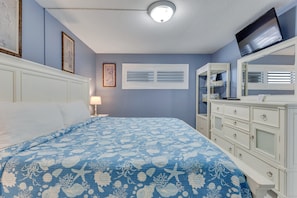 Una camera da letto con un letto, una cassettiera e un televisore appeso al muro.